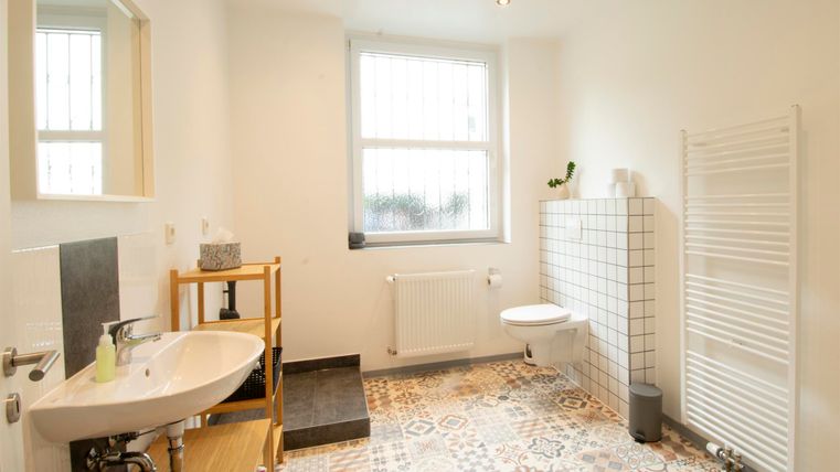 Ein modernes Badezimmer mit buntem Fliesenboden und viel natürlichem Licht. Es ist hell und minimalistisch eingerichtet.