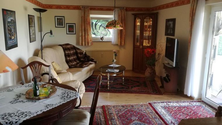 Ein gemütliches Wohnzimmer mit einer bequemen Couch und einem Tisch. Bunte Teppiche und verschiedene Dekorationen verleihen dem Raum eine einladende Atmosphäre.