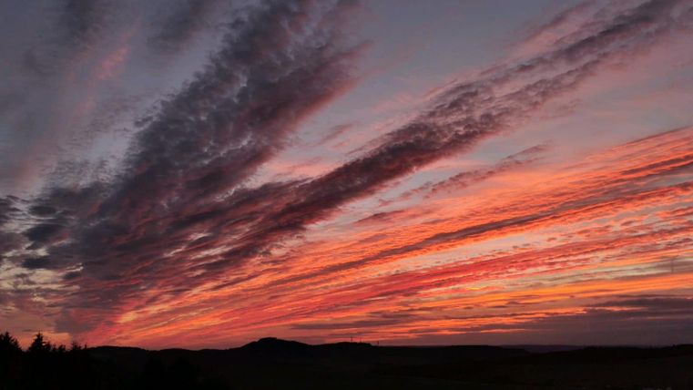 A stunning sunset with vibrant colors in the sky. The clouds drift in various patterns across the landscape.