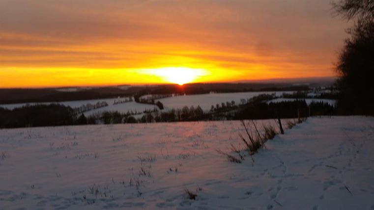 Ein schöner Sonnenuntergang über einer verschneiten Landschaft. Die bunten Farben des Himmels spiegeln sich im weißen Schnee wider.