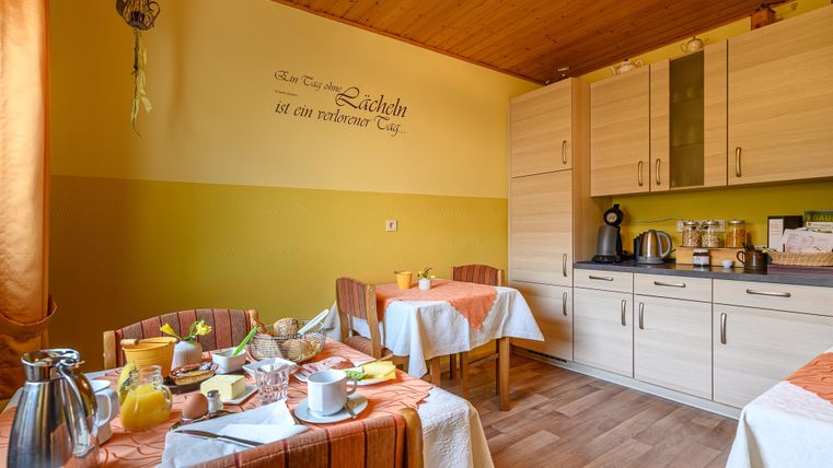 Eine gemütliche Küche mit einem gedeckten Tisch und verschiedenen Frühstücksangeboten. Die Wände sind in sanften Farben gestrichen, und es gibt eine schlichte Küchenzeile.