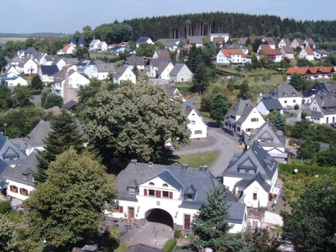 Blick von oben auf die Eisenbahnseidlung "Neue Kolonie". Eine in den  1920 Jahren entstandene Wohnanlage für Eisenbahnbedienstete gruppiert sich in der Form eines Dreiecks, in dessen Mitte ein
großer Laubbaum steht.Sie besteht aus Torhaus, sechs Doppelhäusern und einem eingeschossigen Riegel mit sechs Wohneinheiten. Im Hintergrund stehen viele Häuser aus verschiednen Bauphasen.