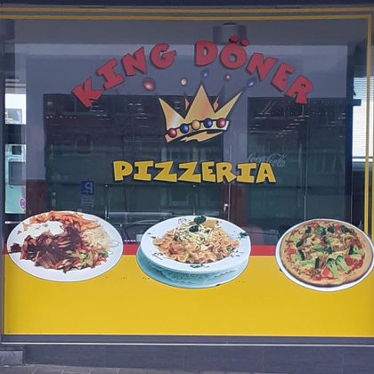 Ein Werbeschild für „King Döner Pizzeria“ mit bunten Bildern von Döner, Pasta und Pizza. Der Hintergrund ist gelb mit einer Krone im Logo.