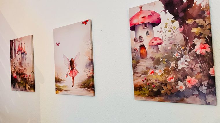 Three charming pictures on a wall depict fairy-tale scenes with fairies, flowers, and a small house with a mushroom hat. The soft colors create a dreamy atmosphere.