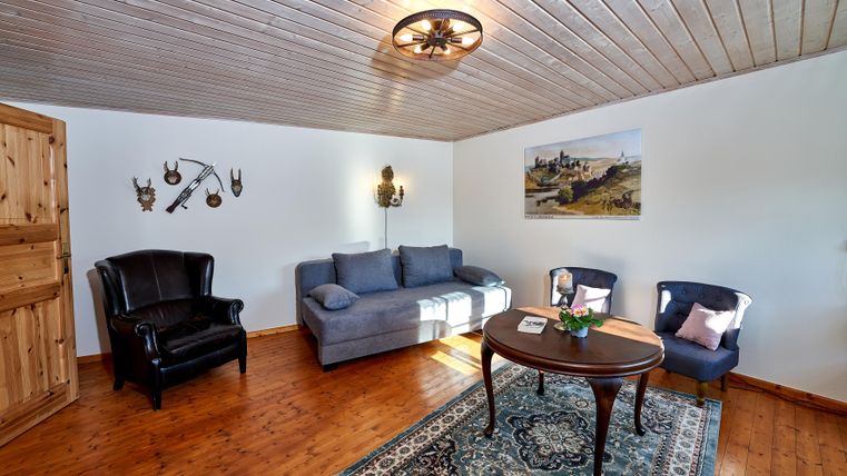 A cozy living room with a blue sofa and two dark blue chairs. The wooden floor and rustic decoration give the space an inviting atmosphere.