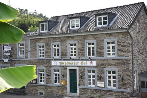 A beautiful, traditional building with a gray facade and many windows. The sign "Weilbacher Hof" is clearly visible.