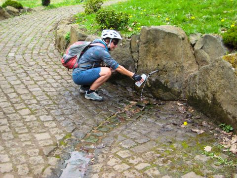 Fietser bij de bron die zijn fles vult