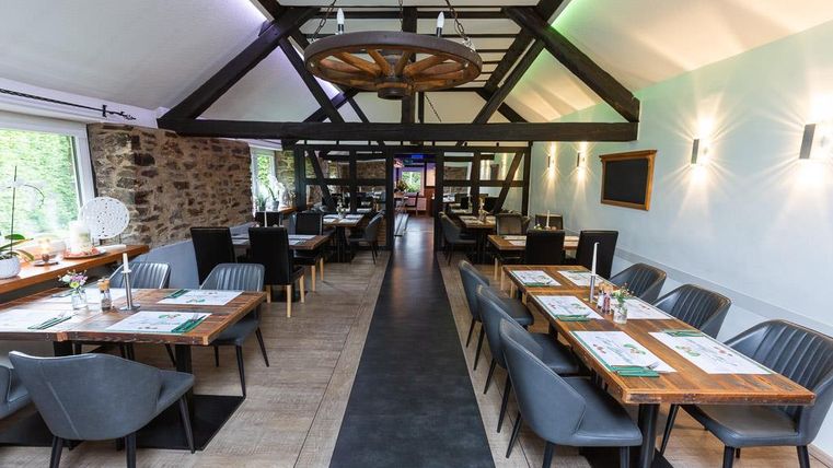 A modern restaurant with wooden decor and elegant tables. The atmosphere is inviting and bright.