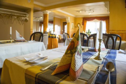 Ein elegantes Restaurant mit schön gedeckten Tischen. Die Tische sind mit Stoffservietten und Kerzen dekoriert.