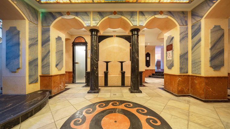 Een stijlvolle interieur met gebogen muren en elegante zuilen. De vloer is ontworpen met een patroon van cirkels en vierkante tegels.