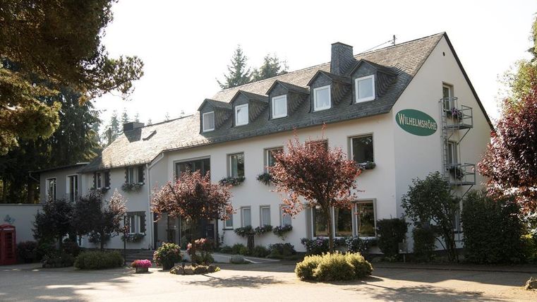 A cozy building with an inviting entrance. Surrounded by trees and flowering shrubs, it exudes a friendly atmosphere.