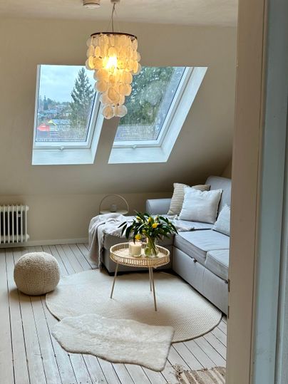 Een lichte, uitnodigende woonruimte met dakramen en moderne meubels. De inrichting is gezellig en minimalistisch vormgegeven.