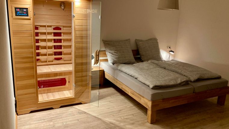 Ein modernes Schlafzimmer mit einem großen Doppelbett und einer Holzsauna. Das Zimmer ist hell und gemütlich eingerichtet.