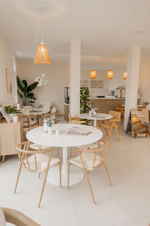 A modern café with bright walls and wooden accents. White tables and chairs create an inviting atmosphere.