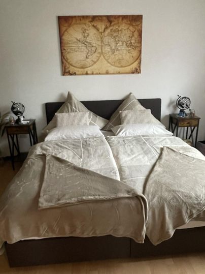 Een gezellig slaapkamer met een tweepersoonsbed en moderne nachtkastjes. Aan de muur hangt een antiek ogende kaart.