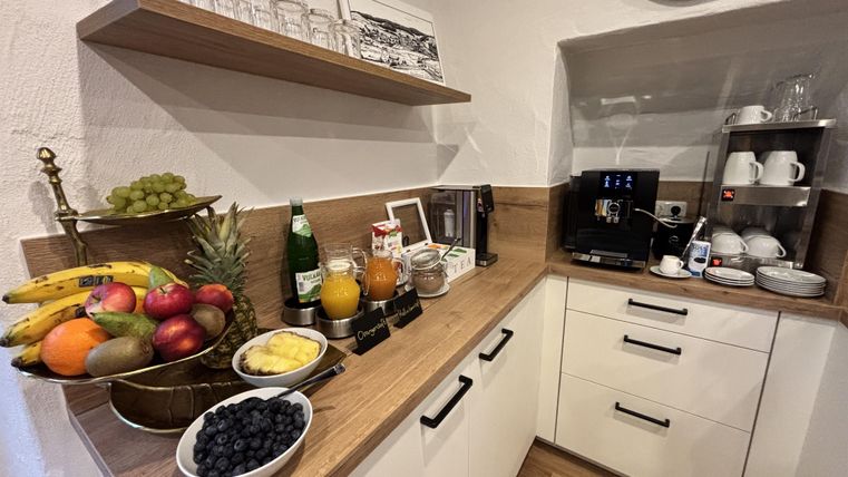 Küchenzeile mit darauf angerichteter Obstplatte mit Kaffeemaschine und Tassen.