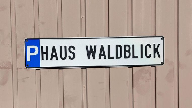 Ein Schild mit dem Text „P Haus Waldblick“. Es zeigt den Parkplatz für das Haus Waldblick an einer Wand.