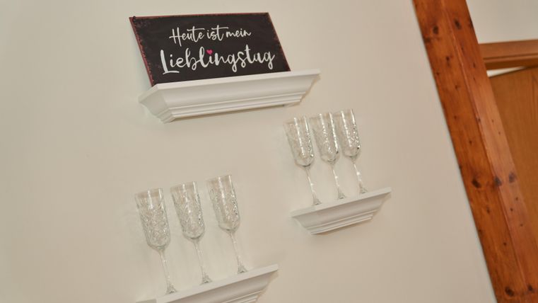 A modern wall shelf with champagne glasses and a sign that says "Today is my favorite day". The glasses are arranged symmetrically and give the room a festive atmosphere.