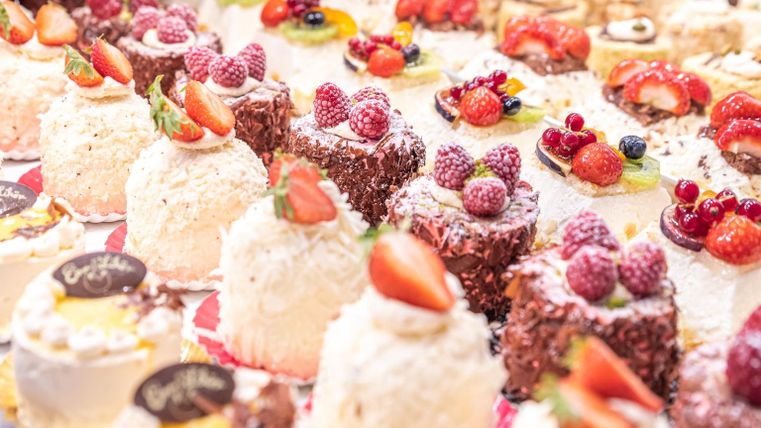 A selection of delicious cakes and pastries with fresh fruits. The treats are colorfully decorated and attractively arranged.
