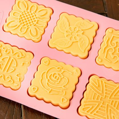 Ein Silikonform mit dekorativen Mustern für Kekse. Die Form enthält sechs verschiedene Designs in Gelb.