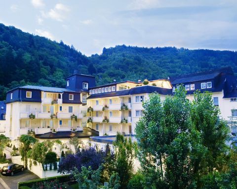 Een modern gebouw in de bergen, omringd door bomen en planten. De lucht is helder en de sfeer is kalm en uitnodigend.