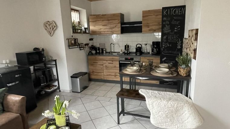 Een moderne keuken met houten kasten en een kleine eethoek. De ruimte is helder en gezellig ingericht.