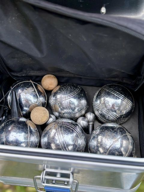 A sports bag with several silver boules and some wooden balls. The balls are neatly arranged inside the bag.