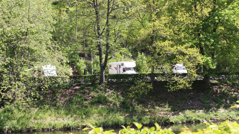Ein Wohnmobilpark in einer grünen, bewaldeten Umgebung. Der Fluss fließt in der Nähe, umgeben von frischen Blättern.