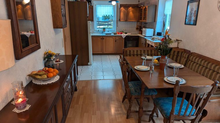 An inviting kitchen with a dining table and colorful fruits. The warm atmosphere is emphasized by wood and pleasant lighting.