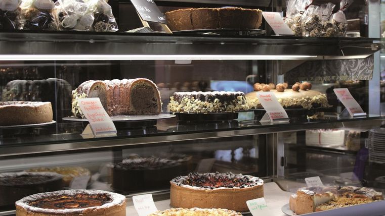 A display case with various delicious cakes and tortes. The selection includes chocolate cake, cheesecake, and fruit tarts.