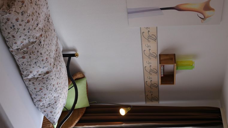 Ein gemütliches Schlafzimmer mit einem Bett, Kissen und Dekoration an der Wand. Die Farben sind warm und einladend.