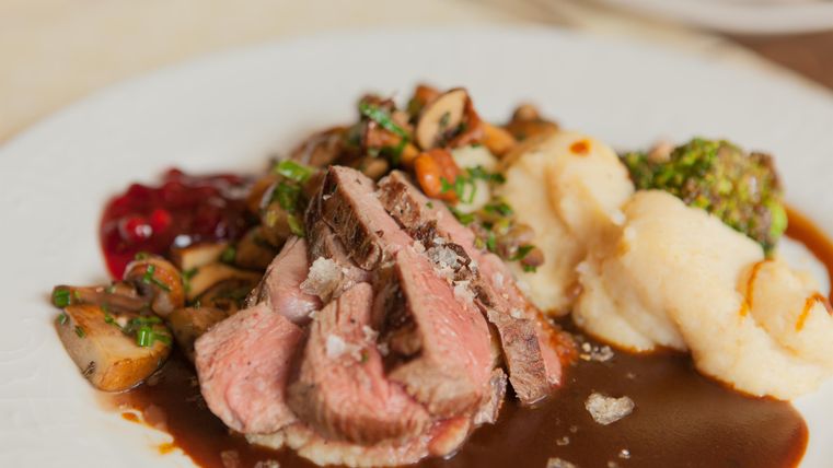 Een heerlijke plaat met gebraden vlees, geserveerd met puree en groenten. Daarbij is er een smakelijke saus en cranberrysaus.