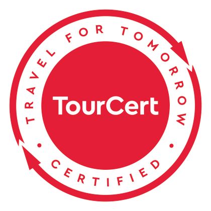Ein rotes Zertifikatssiegel mit dem Schriftzug "TourCert". Es steht unter dem Motto "Travel for Tomorrow" und zeigt die Zertifizierung für nachhaltiges Reisen an.