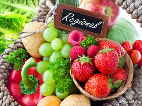 Vlechtmand met talloze soorten fruit en groenten erin, zoals paprika, aardappelen, appels, aardbeien, frambozen, druiven en sla. Daarop een klein houten bord met de tekst "Regionaal".