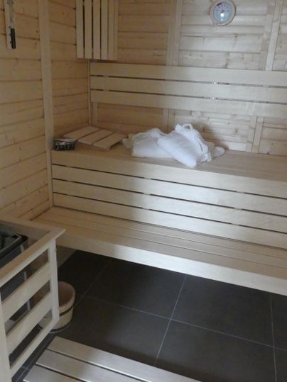 Eine saubere Sauna mit Holzverkleidung und Bänken. Auf der oberen Bank liegen Handtücher.
