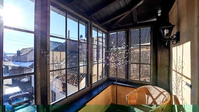 A cozy winter garden with large windows and a wicker chair. The sun is shining in, creating a bright, inviting atmosphere.