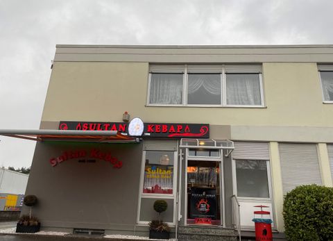 Ein Restaurant mit dem Namen "Sultan Kebab" an einer grauen, bewölkten Tag. Die Fassade ist schlicht und gut sichtbar.