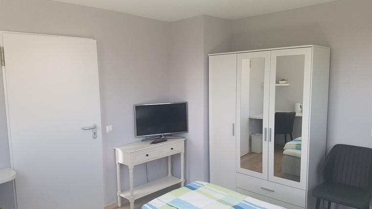 A bright, cozy room with a double bed and a television. The room features a wardrobe and a small table.