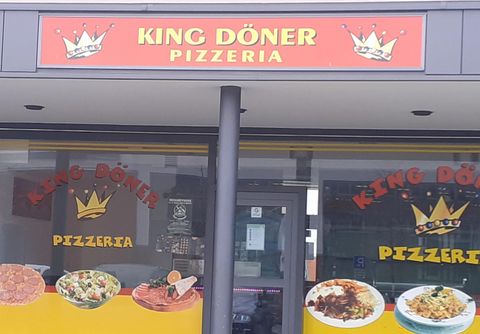 Ein Restaurant mit dem Namen "King Döner Pizzeria". Die Fassade zeigt verschiedene Gerichte und ein einladendes Ambiente.