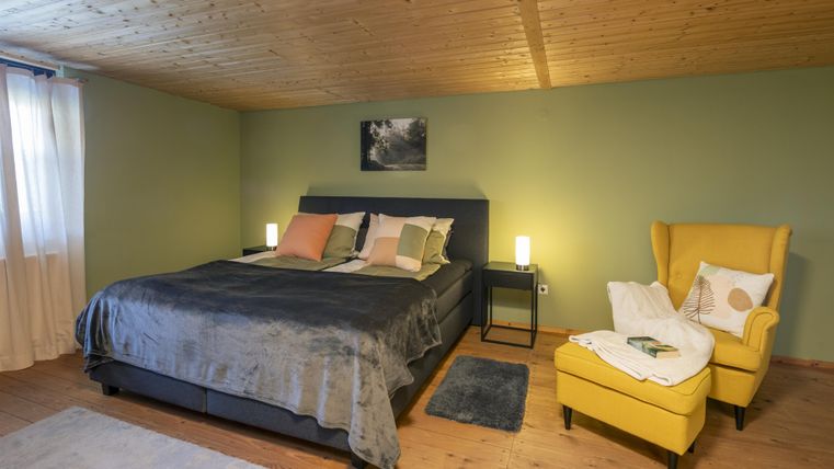 A cozy bedroom with a large bed and soft colors.
A yellow armchair and gentle light create an inviting atmosphere.