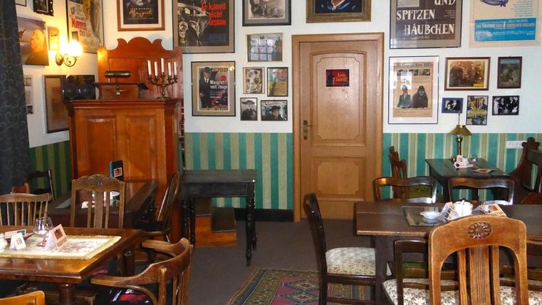Cozy room with wooden furniture, green walls, and numerous movie posters. A rug lies on the floor, and a cabinet stands in the corner.
