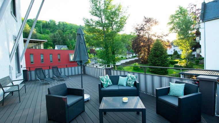 Eine gemütliche Terrasse mit Sitzgelegenheiten und schönem Blick auf die grüne Umgebung. Der Sonnenuntergang sorgt für eine entspannte Atmosphäre.