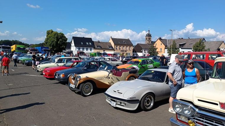Een rij vol oldtimers met bezoekers eromheen