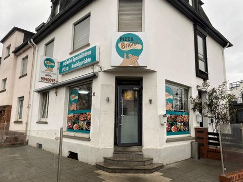 Ein Restaurant mit einer hellen Fassade und großen Fenstern. Die Schilder zeigen verschiedene Speisen und das Ambiente wirkt einladend.