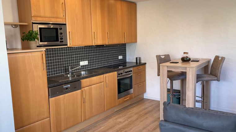 Eine moderne Küche mit Holzschränken und einer kleinen Essecke. Sie ist hell und freundlich gestaltet.