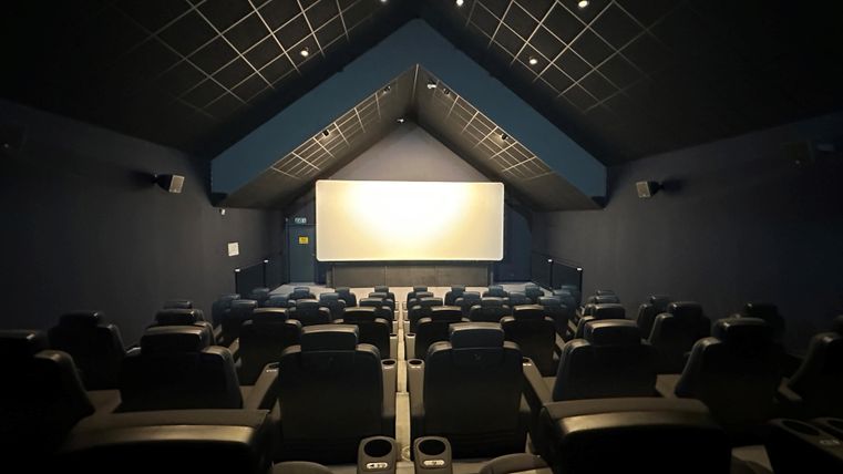 An empty, modern cinema with comfortable seats. The screen is ready for the film.