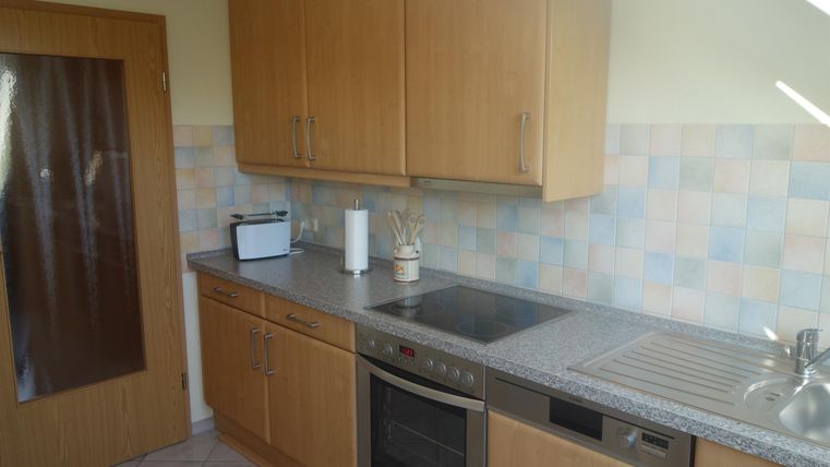 Een moderne keuken met houten kasten en een lichte, vriendelijke sfeer. Het werkgebied is goed georganiseerd en heeft verschillende huishoudelijke apparaten.