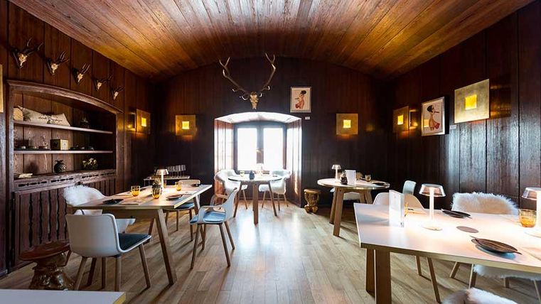 Een gezellig restaurant met donkere houten wanden en een warme ambiance. Tafels zijn elegant gedekt en uitgerust met moderne stoelen.