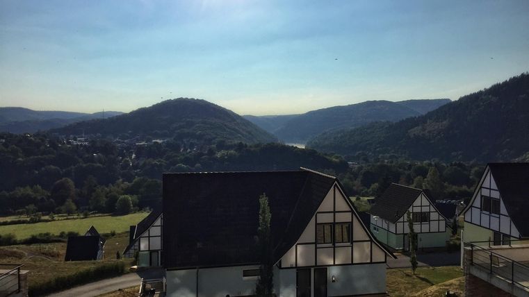 Eine malerische Landschaft mit sanften Hügeln und einem klaren Himmel. Im Vordergrund sind moderne Häuser zu sehen.