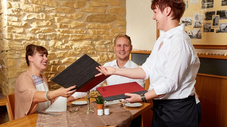 Een restaurantbezoek met gasten die een menu ontvangen. Een ober serveert vriendelijk de menukaarten aan een stel aan tafel.